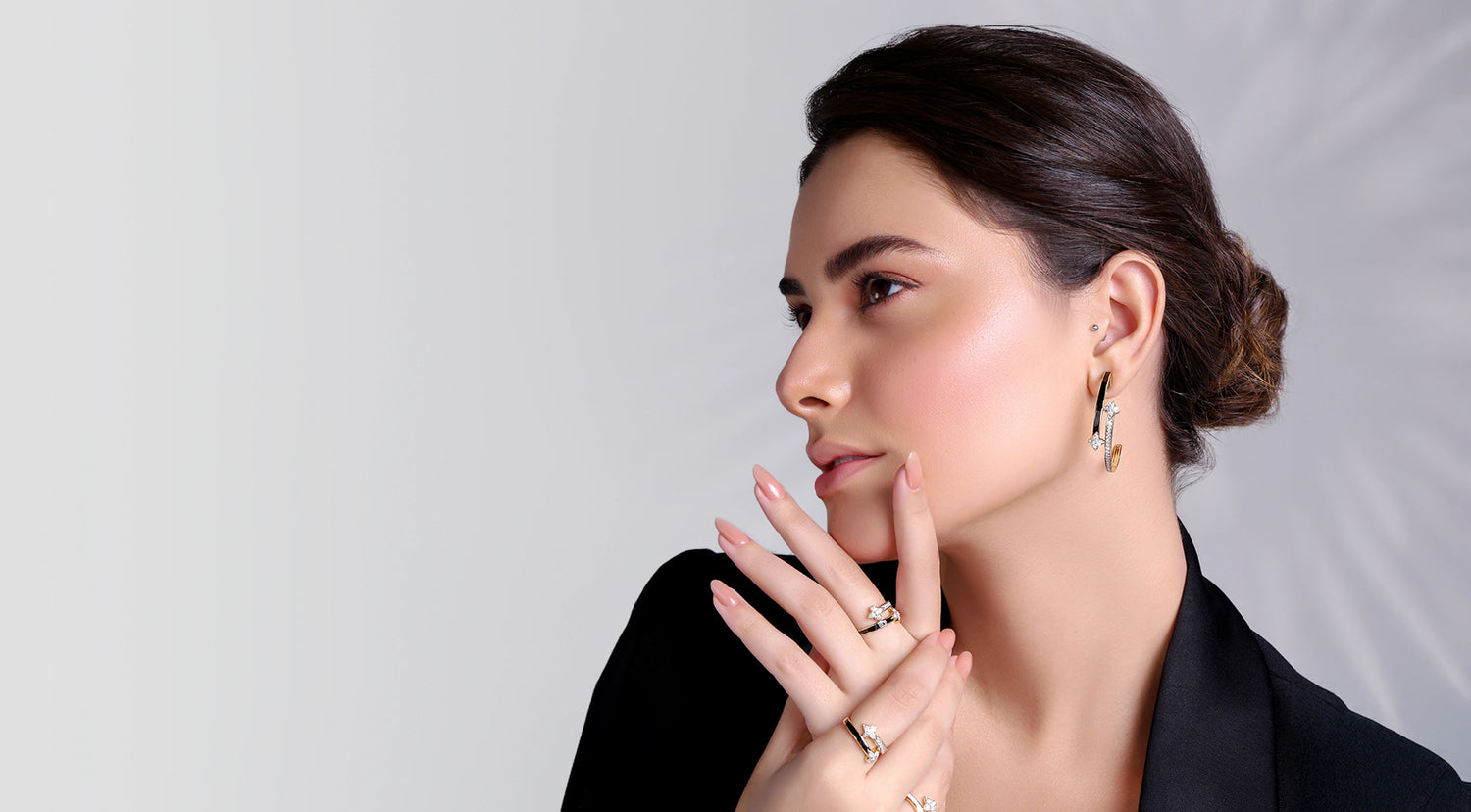 Woman wearing earrings and a ring, with a plain background