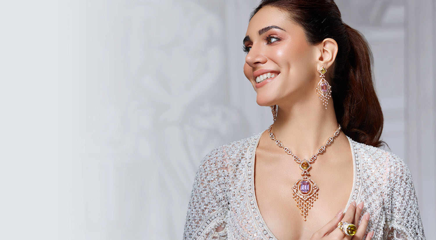 Woman wearing a necklace with a large pendant on a plain background