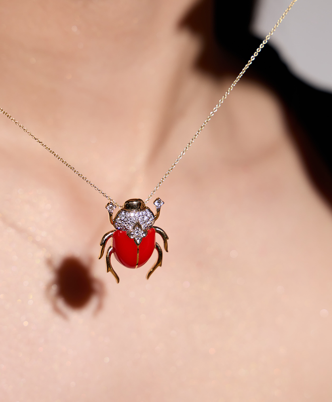 Red scarab pendant necklace on a person's neck with a blurred background